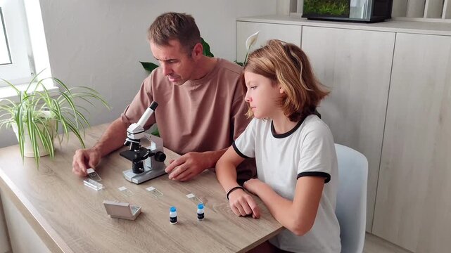 Cute girl with smiling dad enthusiastically studying plants under child microscope. Family having fun discovering world of plants through the lens of optical magnifying instrument