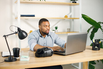 Black male entrepreneur sitting in office and using laptop