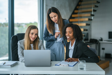 Diverse businesswomen collaborating on laptop during office meeting