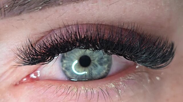 Female grey-green eye opening and looking in camera close-up. Detailed iris, lashes and skin texture with expressive gaze for beauty, emotion, inner world, perception and identity themes.