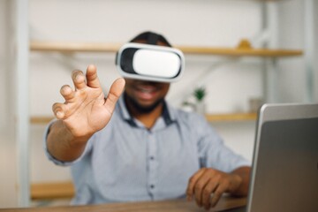 Black male entrepreneur sitting in office and using virtual reality glasses