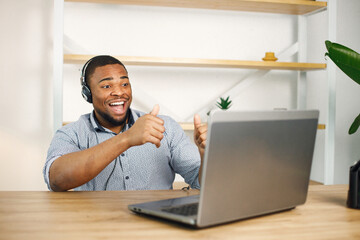 Black man sitting in office, wearing a earphones and make a video call