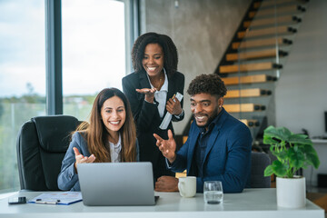 Diverse business team collaborating and celebrating online success in modern office