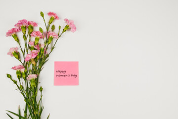 Bouquet of pink carnations with a congratulatory tag for Women's Day, with copy space
