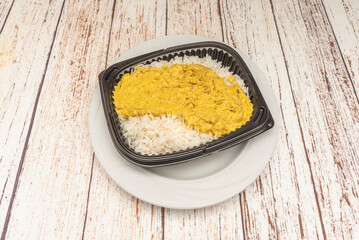 Curried chicken and rice with pieces of chicken breast stir-fried in Thai yellow curry, basmati rice, coconut milk and vegetables, garnished with fresh cilantro and peanuts