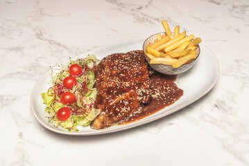 Grilled baby back ribs with a spice rub that forms a dark crust, served with cornbread and dill pickles