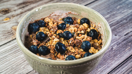 Healthy yogurt bowl with whey protein, crunchy granola, chocolate chunks, and fresh blueberries....