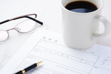 履歴書 - 就職活動（就活）のために、コーヒーを飲みながら、履歴書を用意しているイメージ
