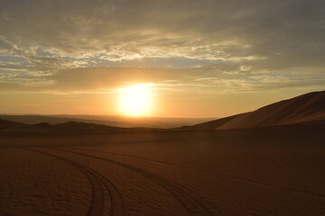 Golden Desert Sunset with Sand Dunes and Tire Tracks