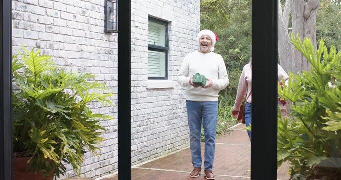 Diverse family approaching glass door on brick path children running sharing gifts and hugging