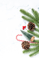 Flat lay of Christmas decorations with fir branches, pine cone, gift boxes, and candy canes on white marble background. Perfect for holiday greeting templates, winter design, and festive ads.