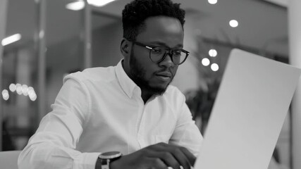 Young professional concentrating on laptop in office setting.