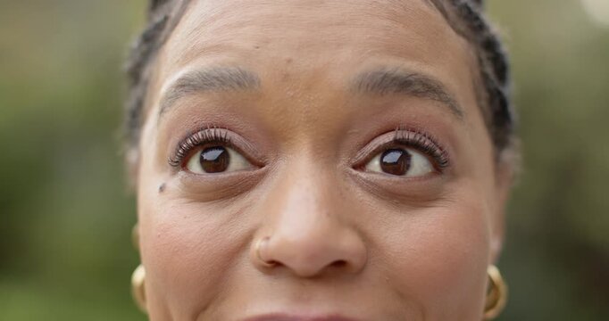 Mid-adult woman reacting to gentle prompt by widening eyes, smiling, then closing eyes in garden