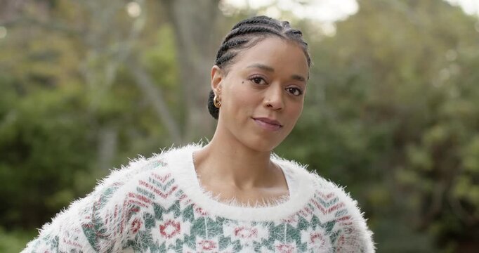Mid adult woman tilting head, crossing arms, smiling warmly in backyard wearing fuzzy sweater
