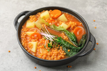 Tasty lentil soup in bowl on grey table, closeup