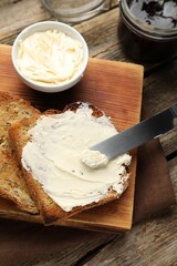 Slices of toasted bread, butter and jam on wooden table, flat lay