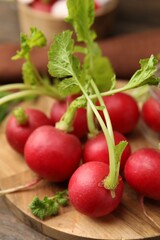 Fresh radishes with green leaves on wooden table, closeup