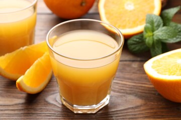 Fresh orange juice, mint and fruits on wooden table, closeup