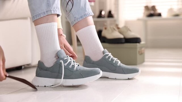 Woman trying on sneakers in shoe store, closeup