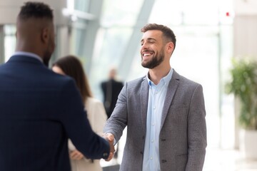 Two smiling diverse businessmen shaking hands to confirm a successful partnership agreement now finalized