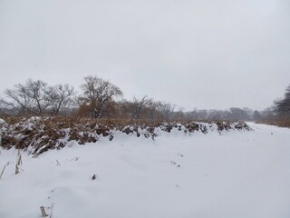 Wide valley riverbed covered in deep winter snow.