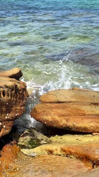 Small waves splash on sandstone rocks by the sea