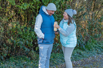 plus size woman thermos, senior male runner taking break morning run, hot drink drinking, together resting on frosty path, enjoying warm drink after exercise, healthy aging, winter morning in nature