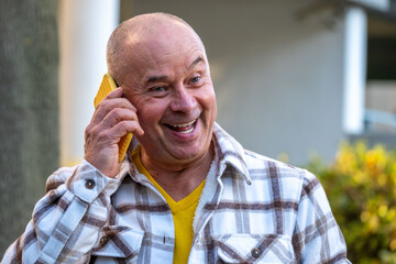 Positive elderly white man 65 years old enjoying technology, senior using modern smartphone, joyful moment surrounded by peaceful nature