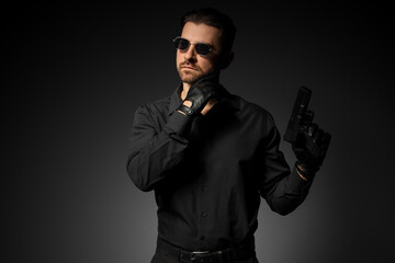 Obraz premium Young man with gun on grey background