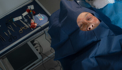 Detailed macro view of a plastic surgeon's gloved hands making an incision on the eyelid of an...