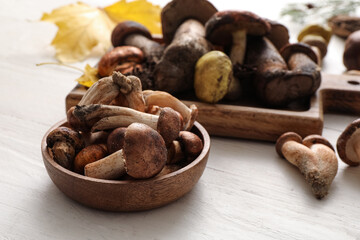 Bowl with fresh mushrooms on white wooden table, closeup