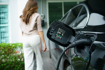 woman charges her electric vehicle at home, showcasing clean and modern living.