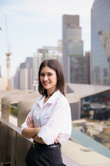 Fototapeta premium Smiling woman standing on a rooftop balcony overlooking the city.