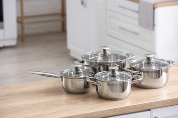 Stainless cooking pots on wooden table in kitchen