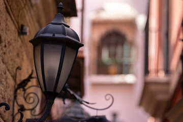 A wrought iron street lamp stands among the historic cityscape of Seville, Andalusia, Spain.