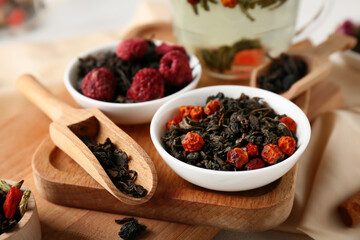 Scoop and bowls with dry fruit tea on wooden board as background, closeup