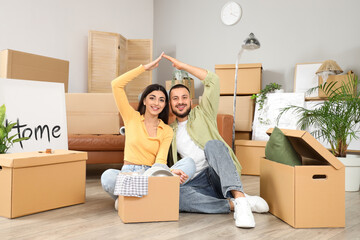 Young couple with boxes making roof sign in rented apartment on moving day © Pixel-Shot