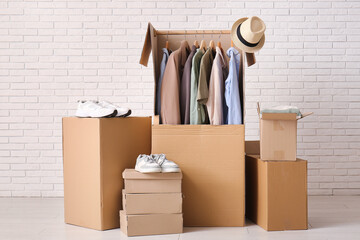 Wardrobe boxes with men's clothes and shoes near white brick wall