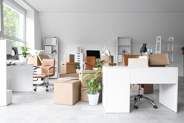 Desks with cardboard boxes in office on moving day