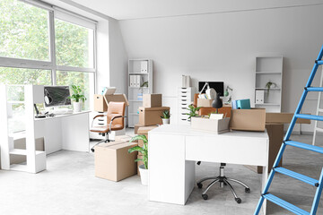 Desks with cardboard boxes in office on moving day
