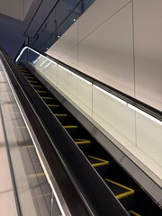 Fototapeta premium Modern Escalator Design: Backlit railings and clean black and white lines in a commercial space