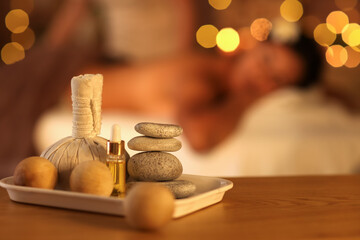Spa stones with massage balls, oil and herbal bag on table in dark salon, closeup