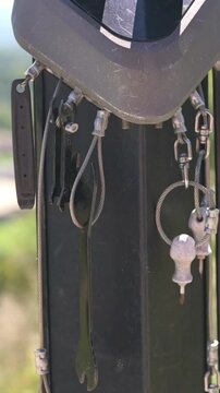 Verti al screen closeup keyring and helmet detail on bike post with blurred park horizon, small keys and ring catching sunlight, calm contemplative mood, subtle wear on metal and soft