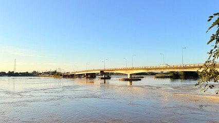 High angle view of strong muddy water current flowing fast around concrete bridge pillar, flood...