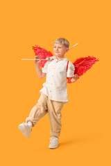 Naklejka premium Cute little happy boy dressed as cupid with bow and arrow on yellow background. Valentine's Day celebration