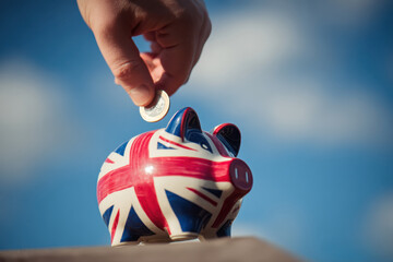 Saving money in a UK union jack piggy bank for budgeting, finance and personal savings concepts