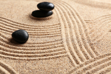 Black spa stones on light sand with lines