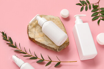 Composition with bottles and jars of cosmetic products on pink background