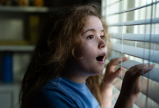 Kid waiting at home. Surprised child waiting at home near window. Surprised kid waiting and looking window out. Kid wait in a indoor moment. Child waiting on surprise by the window.