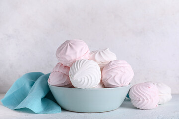 Bowl with sweet marshmallows on table against white background